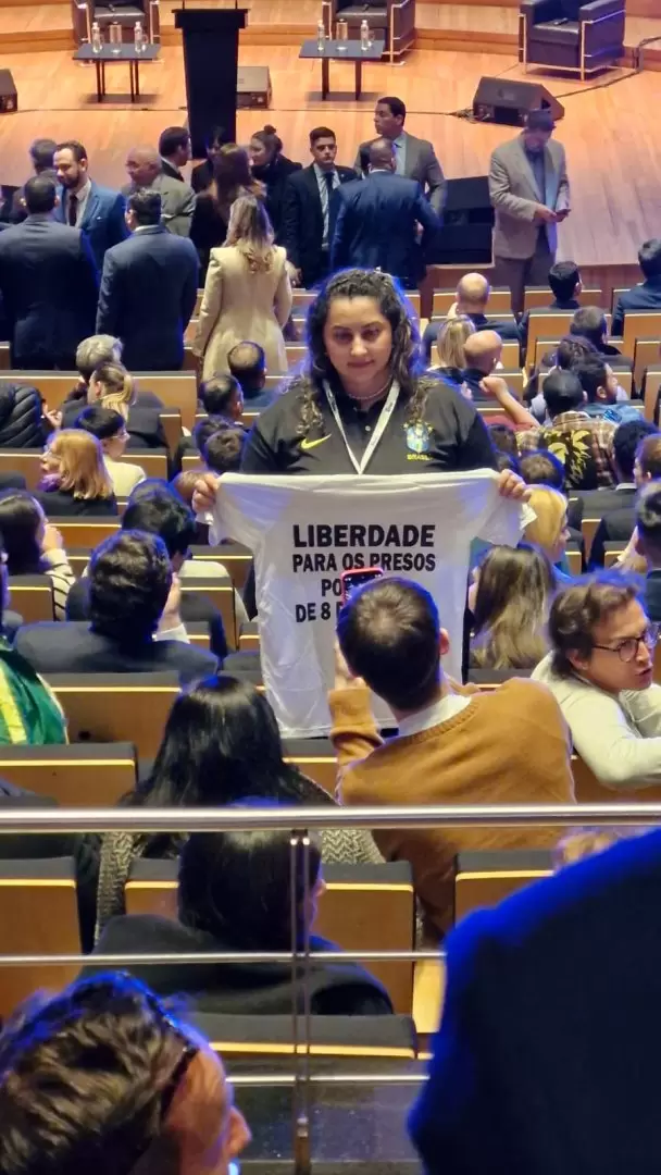 Una persona del pblico con una remera que dice "Libertad para los presos polticos del 8 de enero".